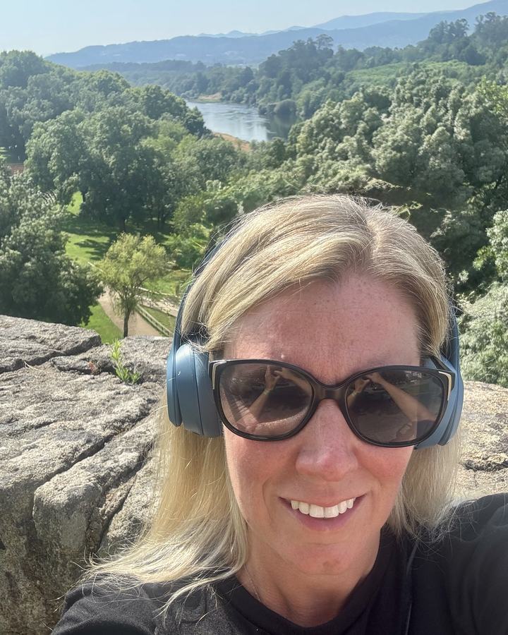 Sylvia wearing headphones on a hilltop above a river valley